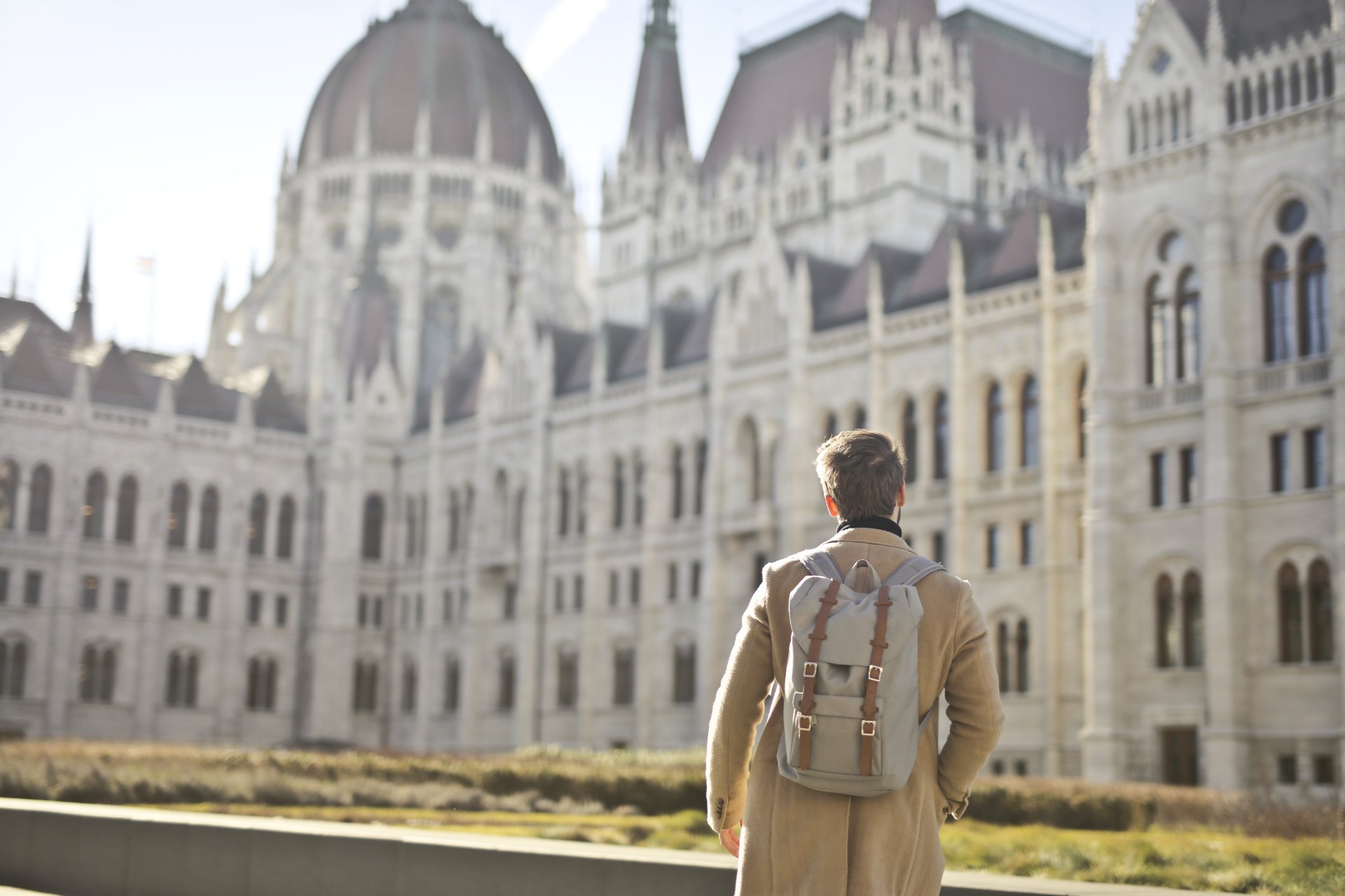 Jeune homme avec un sac à dos devant le Parlement hongrois à Budapest