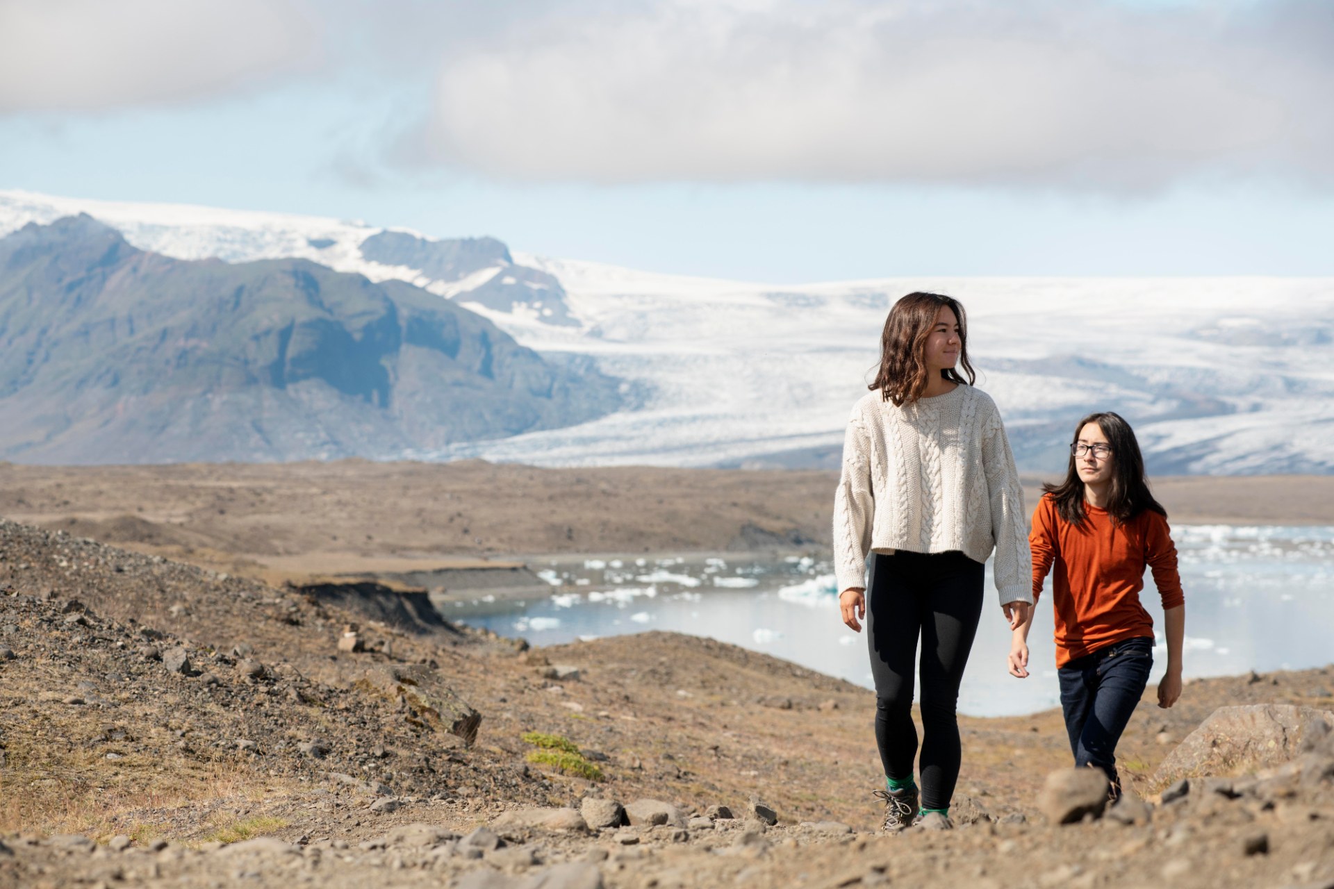 Deux jeunes femmes en randonnée en Islande, avec un glacier et des montagnes en arrière-plan