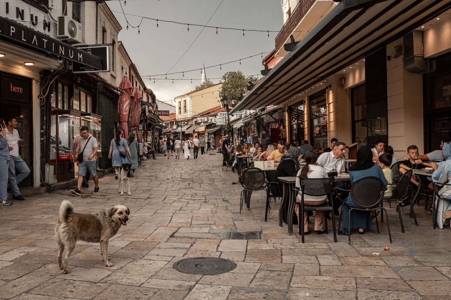 Des gens aux terrasses des cafés dans une ruelle commerçante de la vieille ville de Skopje
