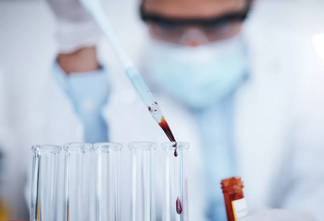 Une chercheuse depose a la pipette un echantillon de sang dans un tube a essai.